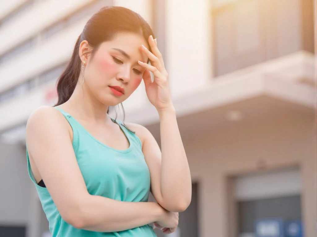 Người phụ nữ đặt tay lên trán ở ngoài trời